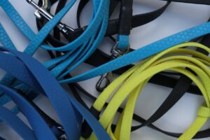 Verschiedene Hundeleinen aus Hexa-Material in Blau, Gelb und Schwarz, übereinandergelegt.