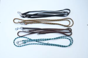 Vier verstellbare Hundeleinen aus verschiedenen Materialien wie Leder, Nylon und Paracord, ordentlich nebeneinander auf weißem Hintergrund arrangiert.
