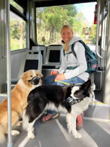 Hundehalterin mit zwei Hunden in der Seilbahn – wetterfeste Jacke und funktionales Outdoor-Equipment