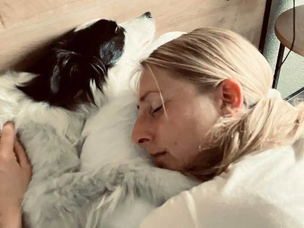 Frau schläft eng an ihren Hund gekuschelt im Bett – Symbol für hundefreundliches Hotel mit echter Wohlfühlatmosphäre