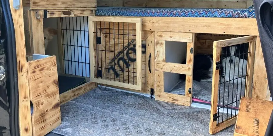 Zwei Hunde liegen in separaten, holzverkleideten Autoboxen – Beispiel für sicheren Hundetransport auf Reisen
