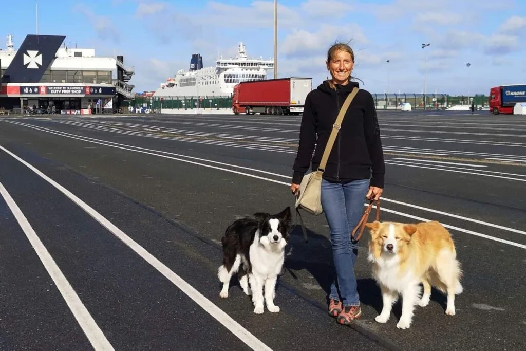Frau mit zwei Hunden am Fährterminal, bereit zur Einschiffung – Beispiel für Reisevorbereitung mit Hund